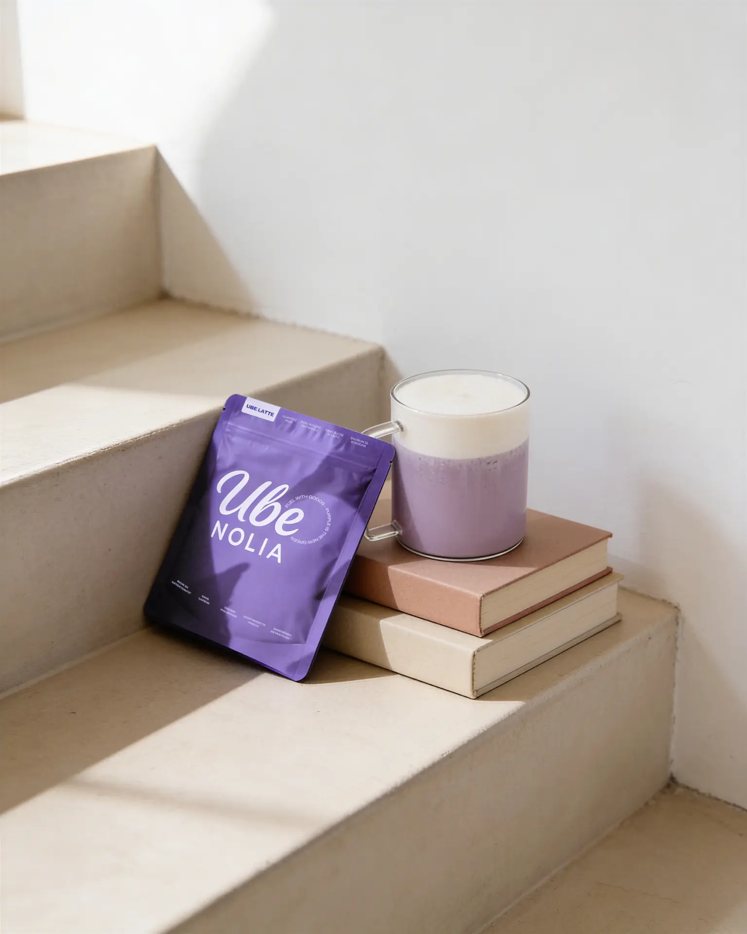 Ube Nolia Ube Pulver Beutel neben einem cremigen Ube Latte auf beigen Stufen