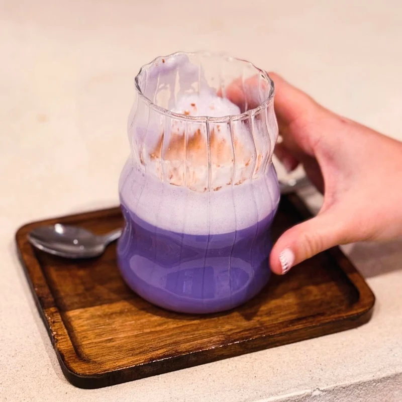 Ube Nolia Ube Latte im Rillenglas auf einem Holztablett