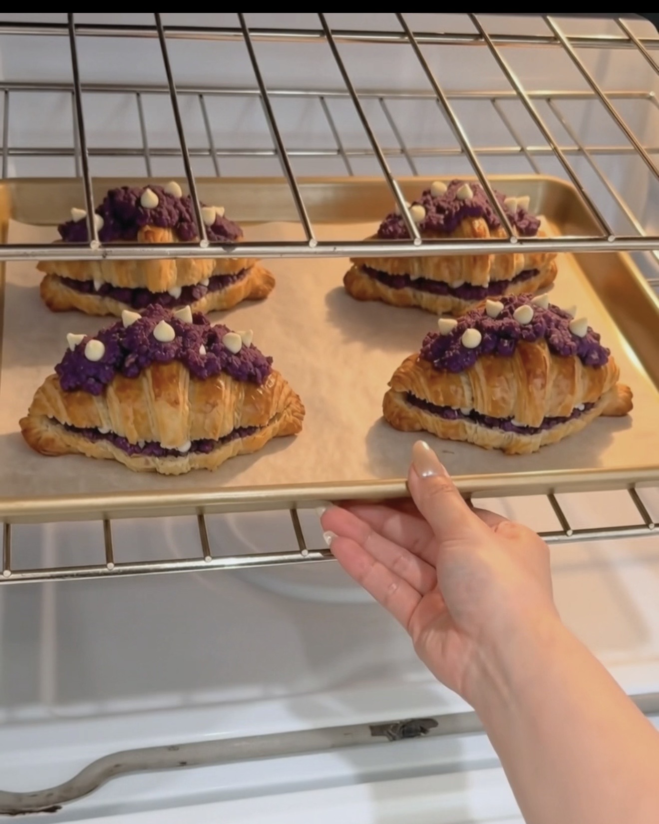 Blech mit UBE NOLIA Ube Crookies frisch aus dem Ofen mit goldenen Croissant-Schichten und lila Ube (purple yam) Keks-Topping mit weißen Schokoladenchips