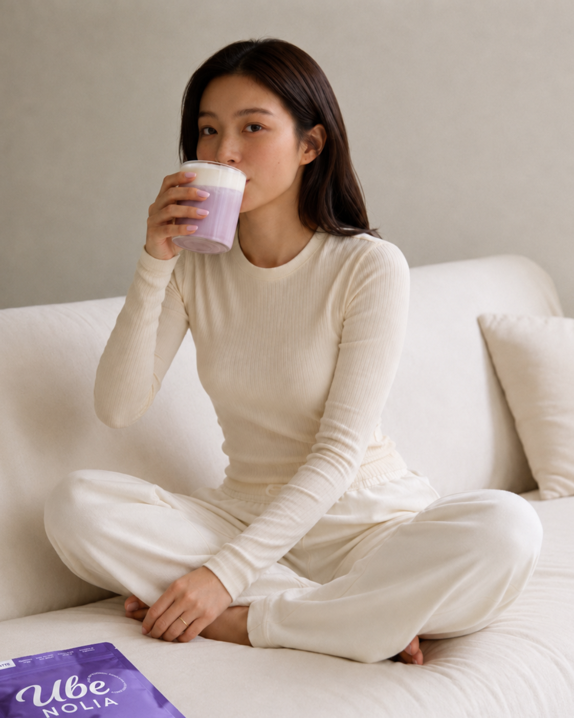 Frau trinkt einen Ube Nolia Ube Latte neben dem Ube Pulver Beutel