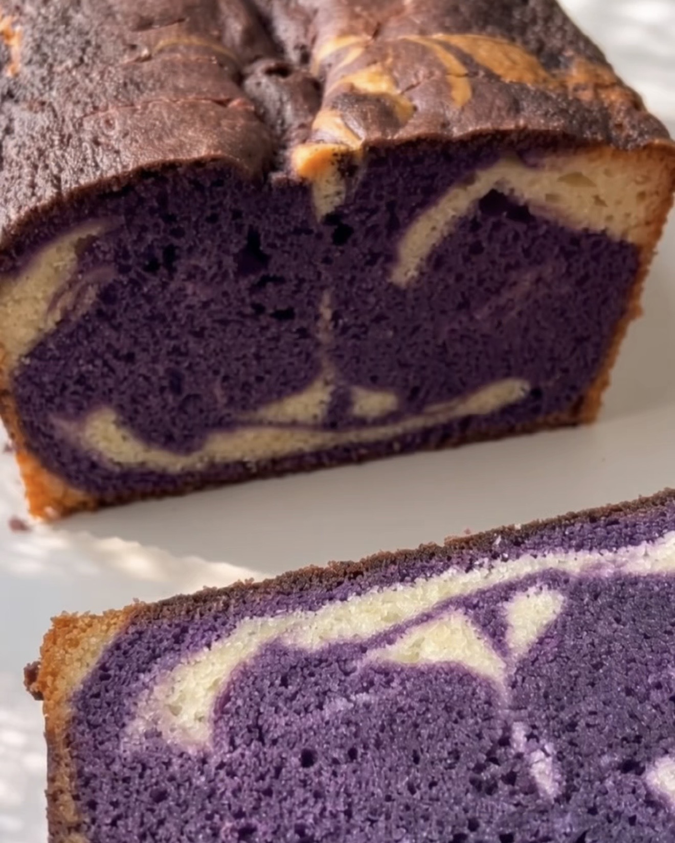 Gebackener Ube Marmor-Pfundkuchen aufgeschnitten, der die lila-vanille-Marmorierung zeigt, hergestellt mit UBE NOLIA Ube-Pulver