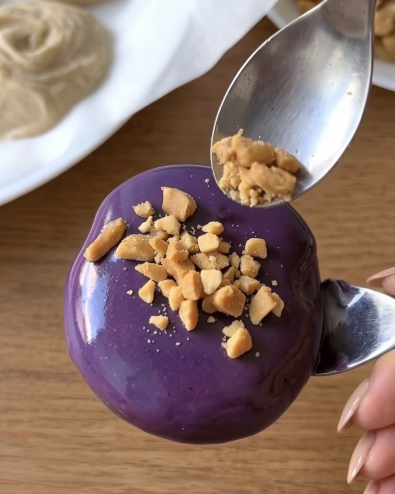 Zerstoßene geröstete Erdnüsse auf ein lila Ube-Weiße-Schokolade überzogenes Ube Nolia gefrorenes Joghurt-Häppchen gestreut