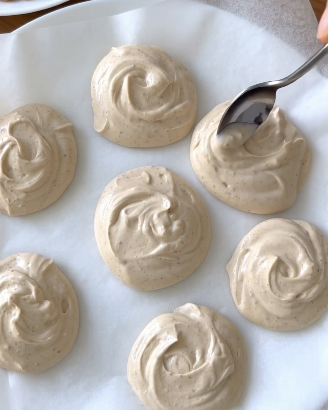 Cremige Erdnussbutter-Griechischer-Joghurt-Kleckse auf Backpapier für Ube Nolia gefrorene Ube-Häppchen