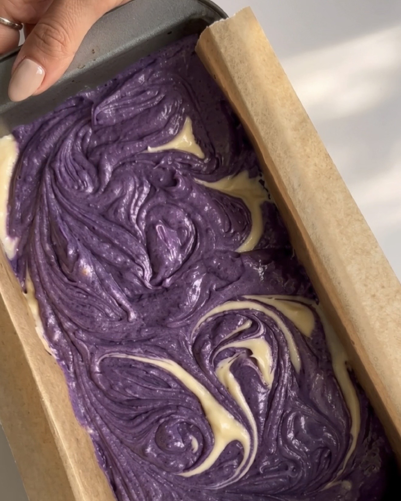 Lila und Vanille-Teige zu einem Marmormuster in der Kastenform für UBE NOLIA Ube Marmor-Pfundkuchen verwirbelt
