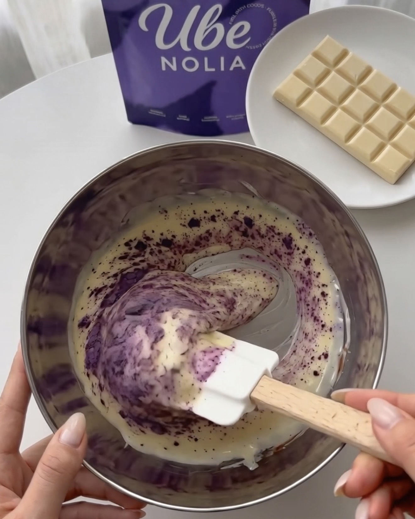 Ube Nolia Ube-Pulver in geschmolzene weiße Schokolade für lila Pistazien-Quinoa-Bites einrühren