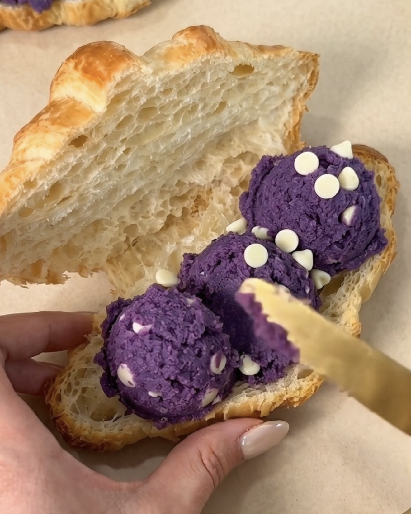 UBE NOLIA lila Ube (purple yam) Weißschokoladen-Chip-Keksteig wird in ein aufgeschnittenes Buttercroissant gefüllt, um einen Ube Crookie herzustellen