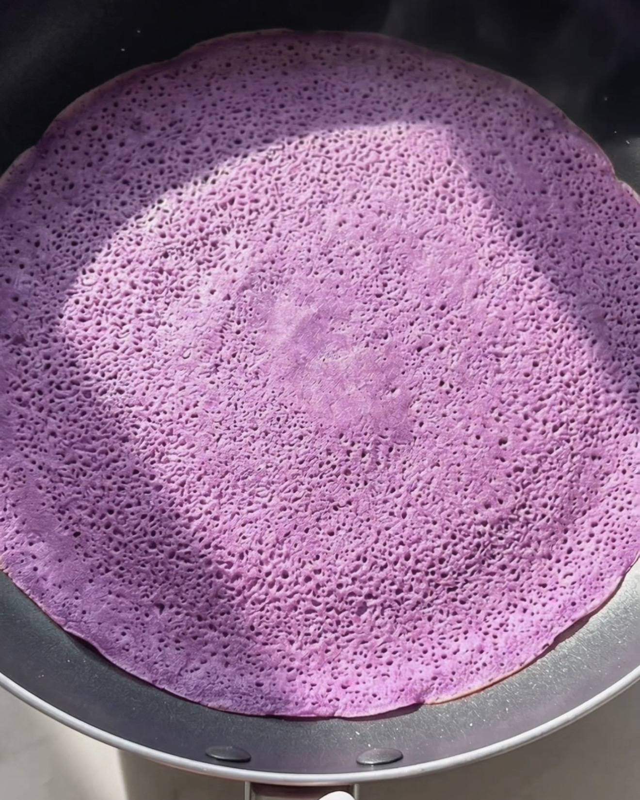 Dünnen lila Ube Dadar Gulung Crêpe in einer beschichteten Pfanne backen