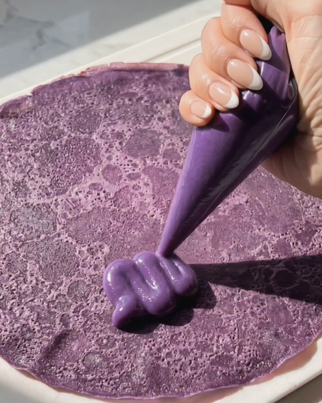 Ube Halaya-Füllung auf einen lila Ube-Crêpe für die Dadar Gulung-Zubereitung spritzen