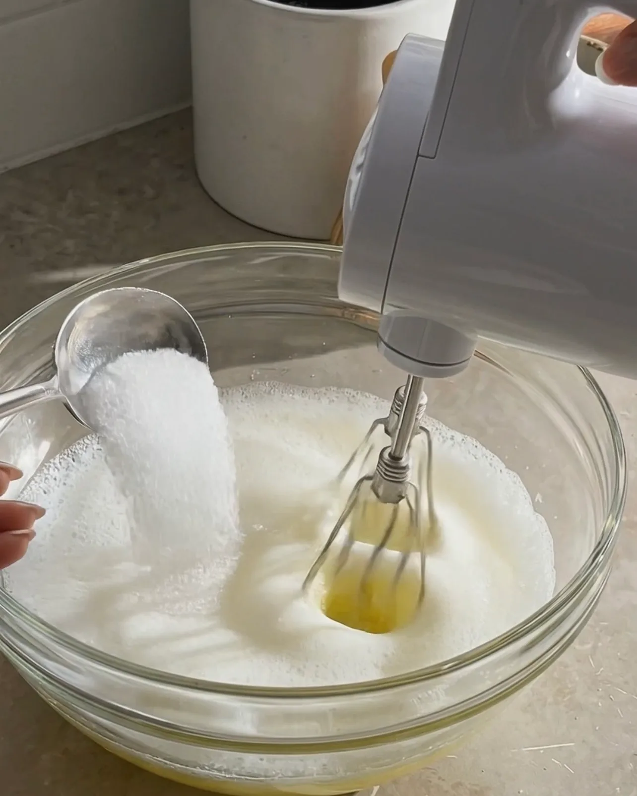 Zucker zu schaumigem Eiweiß hinzufügen, während es mit einem Handmixer für Ube Roll Cake von UBE NOLIA aufgeschlagen wird
