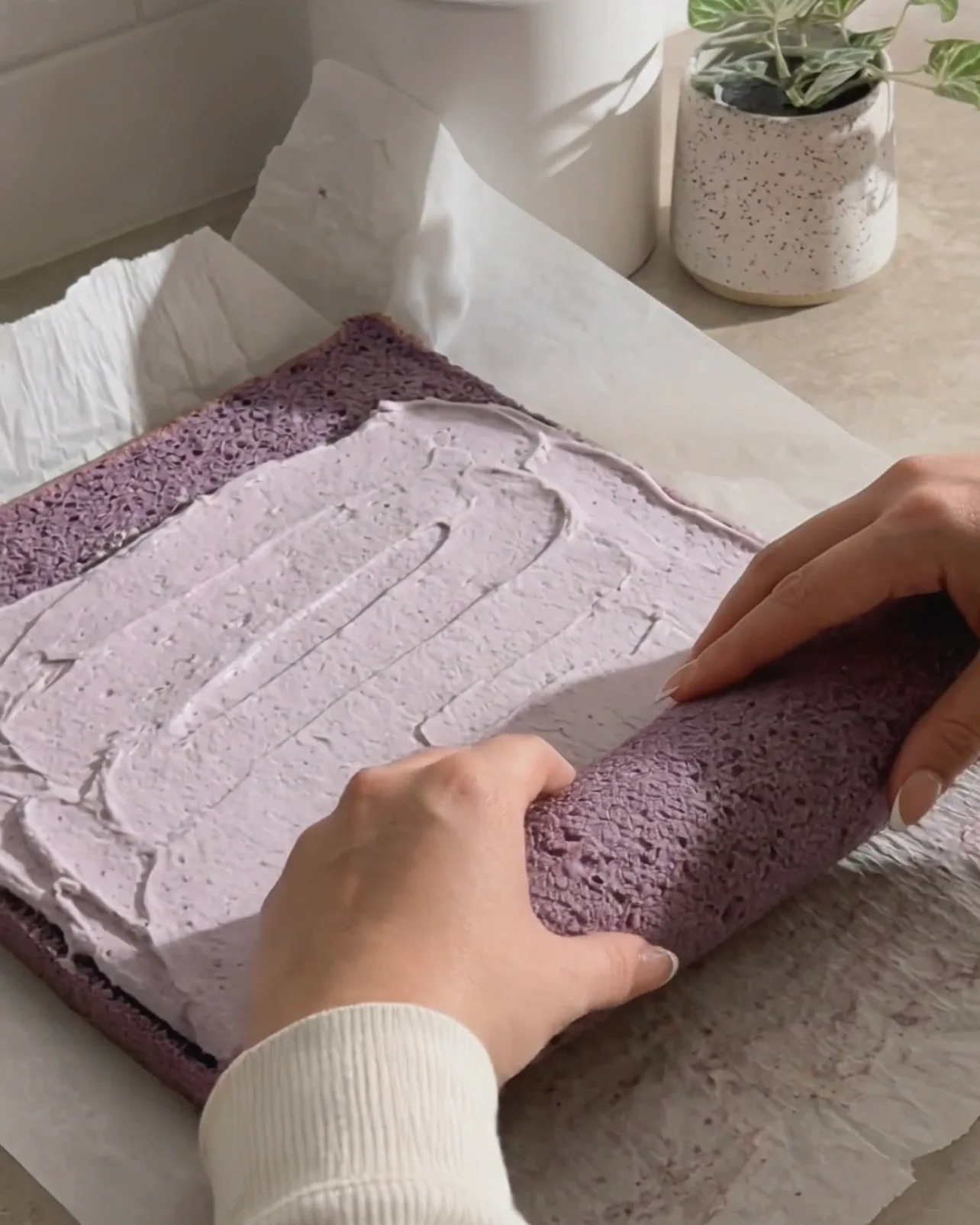 Ube-Schlagsahne auf dem lila Chiffonkuchen verteilen und aufrollen von UBE NOLIA