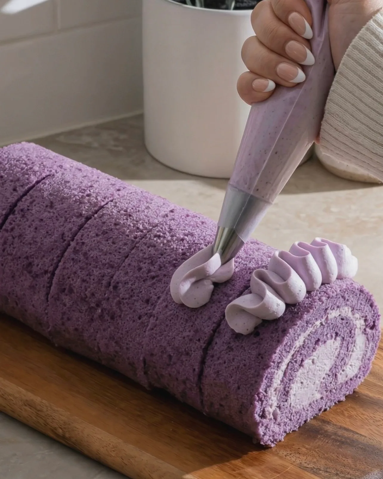 Dekorative Ube-Schlagsahnerosetten auf dem fertigen lila Ube-Roll Cake aufspritzen von UBE NOLIA
