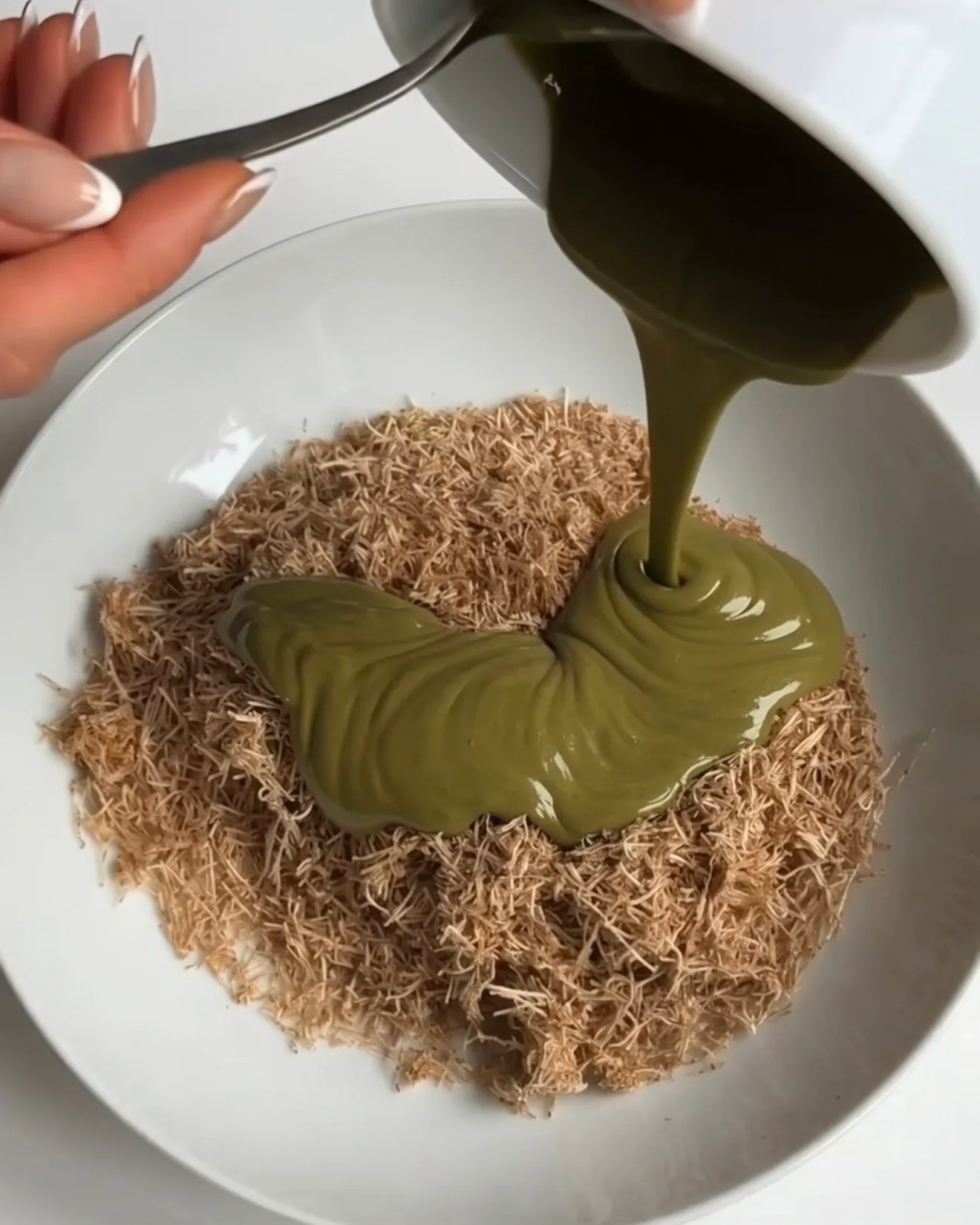 Pistaziencreme über eine Schüssel gerösteten Kataifi-Teig für die Ube Dubai Chocolate Brownie Riegel Füllung von Ube Nolia gegossen