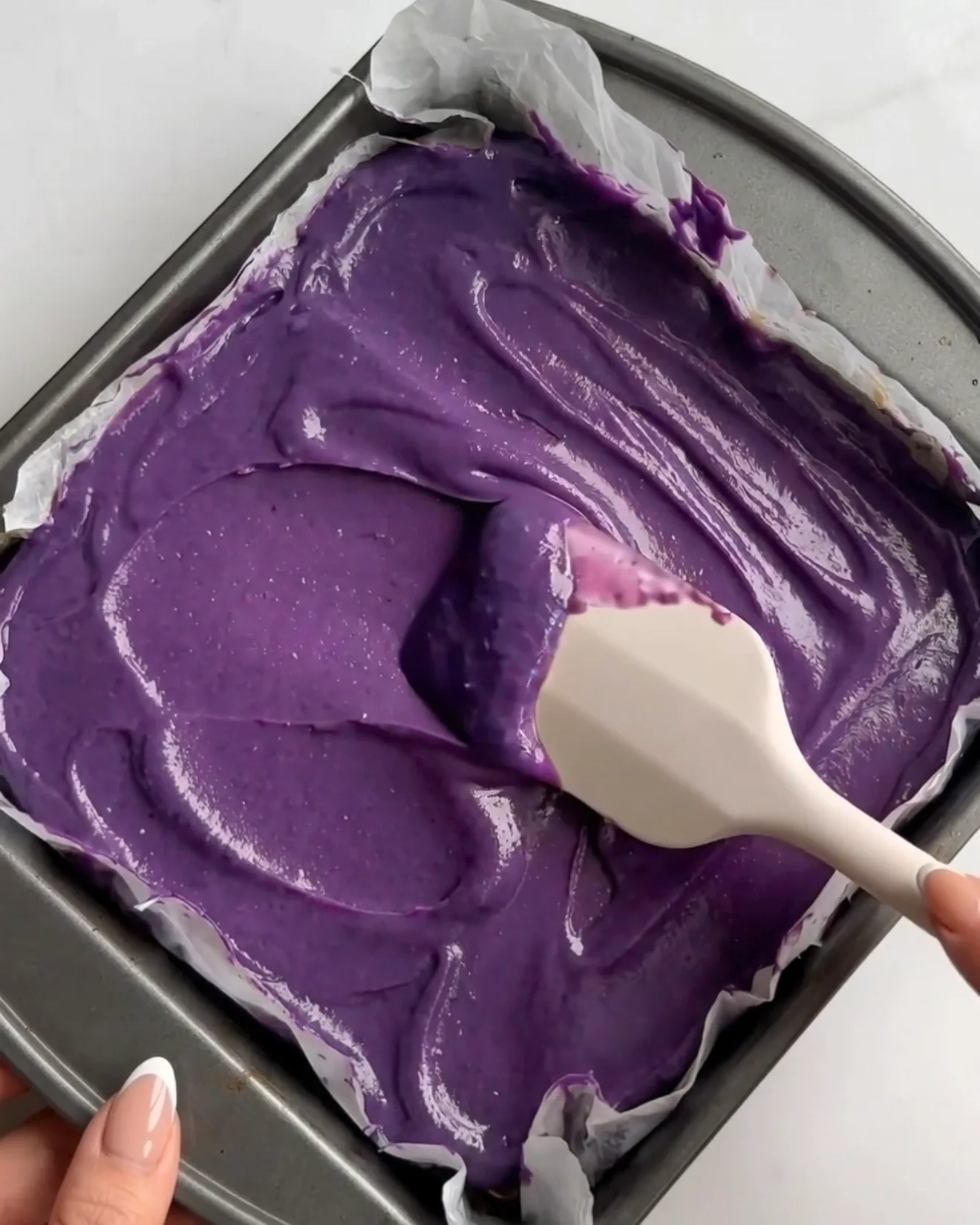 Lebendige lila Ube Weiße Schokoladen Ganache wird über die Pistazien-Kataifi-Schicht für Ube Dubai Chocolate Brownie Riegel von Ube Nolia verteilt